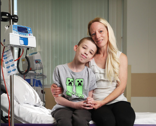 A boy and his mum sitting on a hospital bed.
